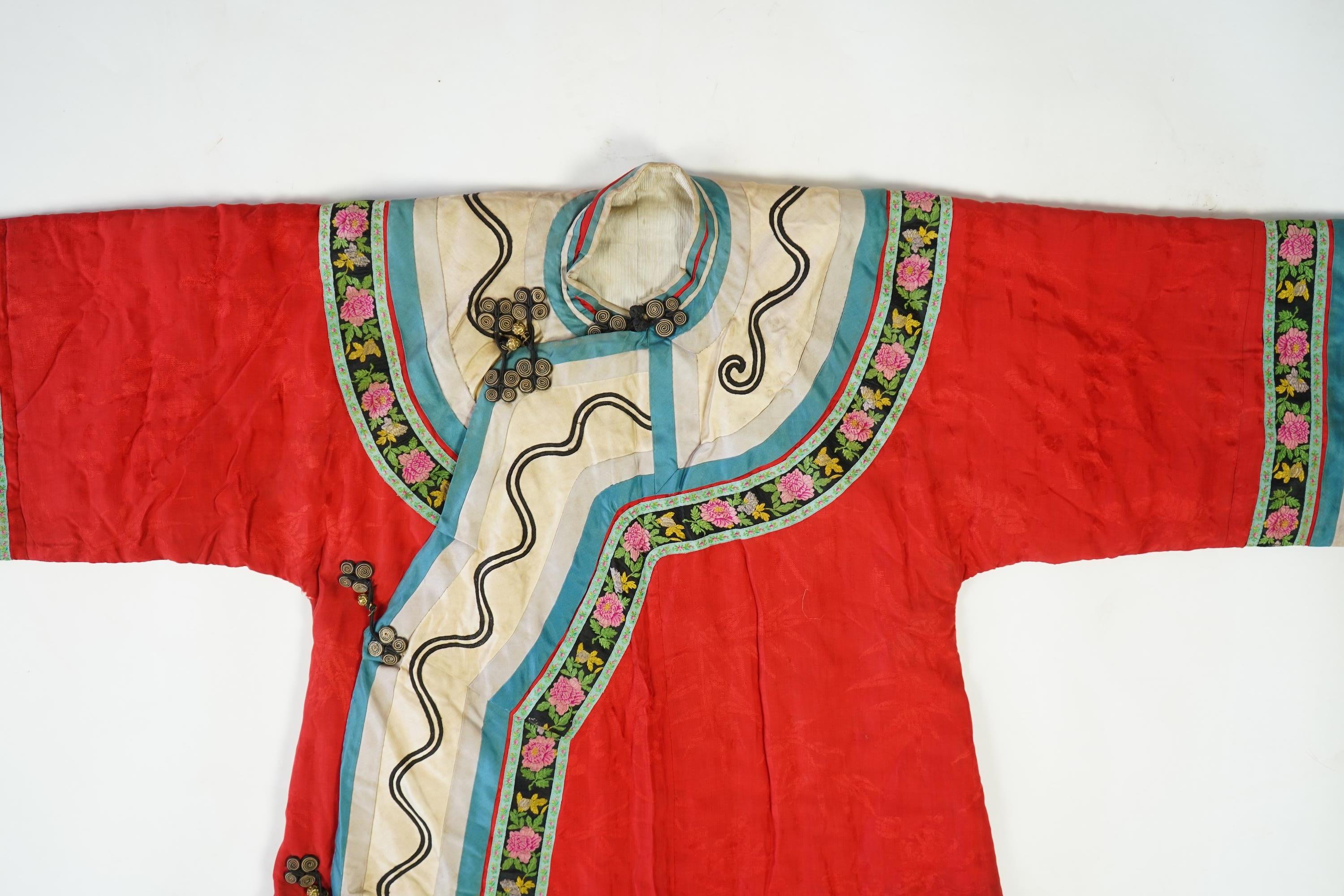 A late 19th century early 20th century Chinese red silk damask quilted Mandarin robe. Decorated with colourful rows braiding and ornate toggling. 116cm long. Condition - minor marks in places, may benefit from specialist